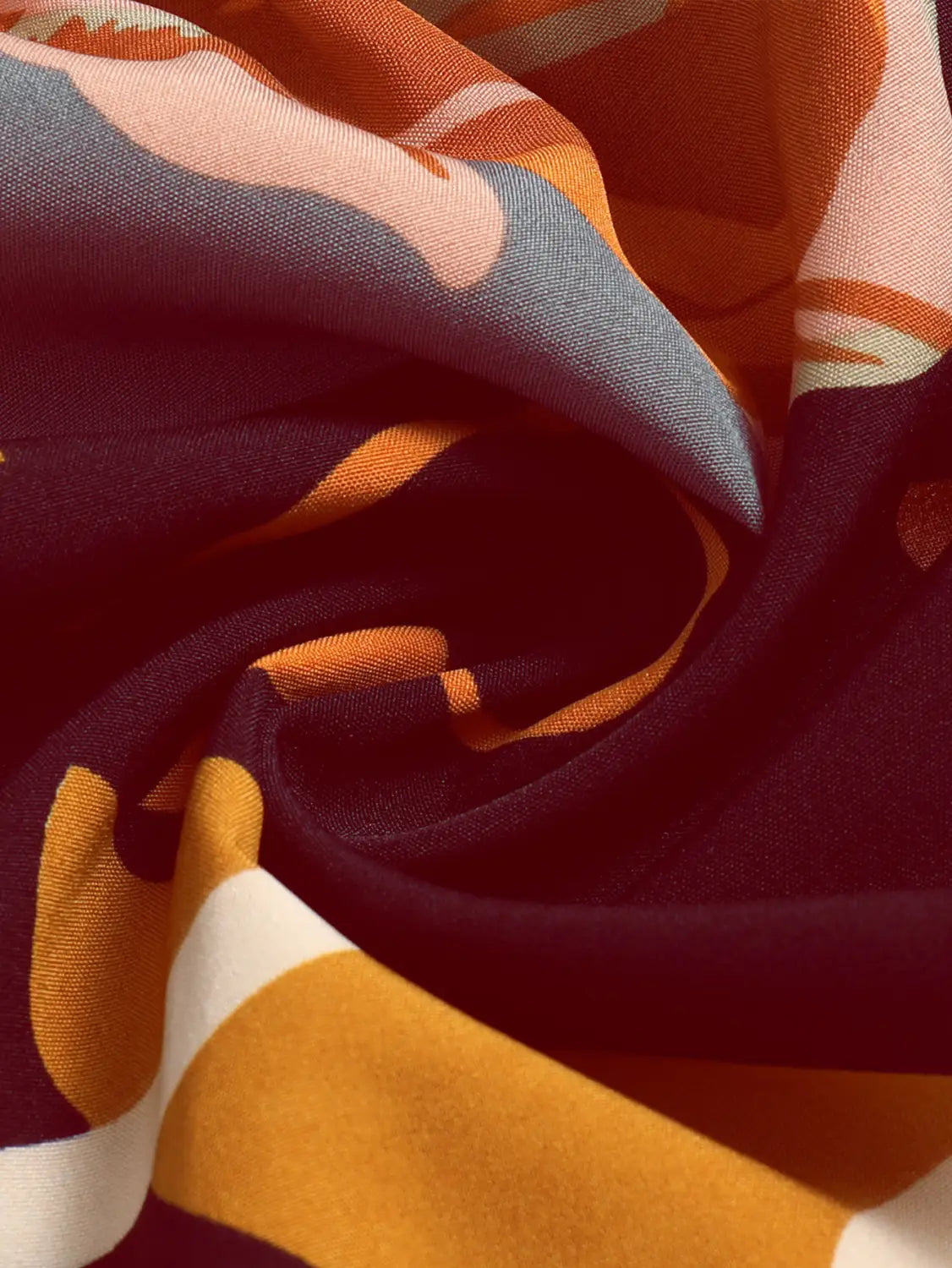 a cream tiered pleated floral print elastic waist skirt displayed with a soft flowing scarf featuring a bold abstract pattern in shades of orange blue-gray and white against a deep maroon background
