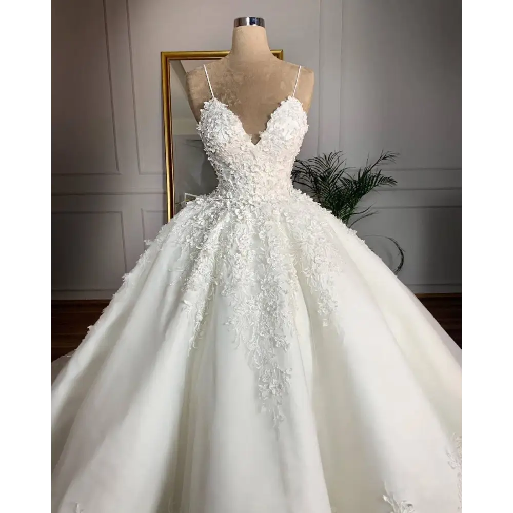 A white lace wedding dress with deep v-neck lace appliqués and a voluminous skirt exuding romantic aura on a mannequin