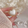 Delicate gold diamond love pearl heart ring with a white glittery center encased in resin and gold-toned bezel