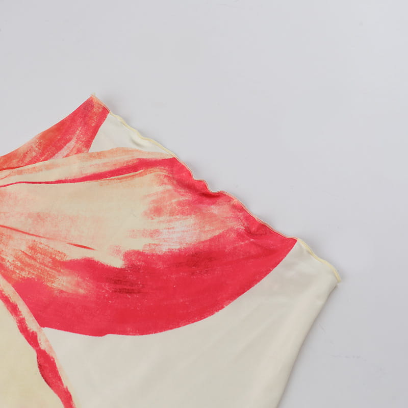 A soft cream-colored silk scarf with a bold abstract red brushstroke design paired with an elegant slim print floral top and skirt set.