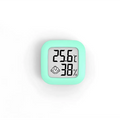 A mint green digital display temperature and humidity meter with electronic humidity measurement and smiling face icon