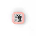 Pink square digital display temperature and humidity meter with smiling baby face icon for humidity measurement