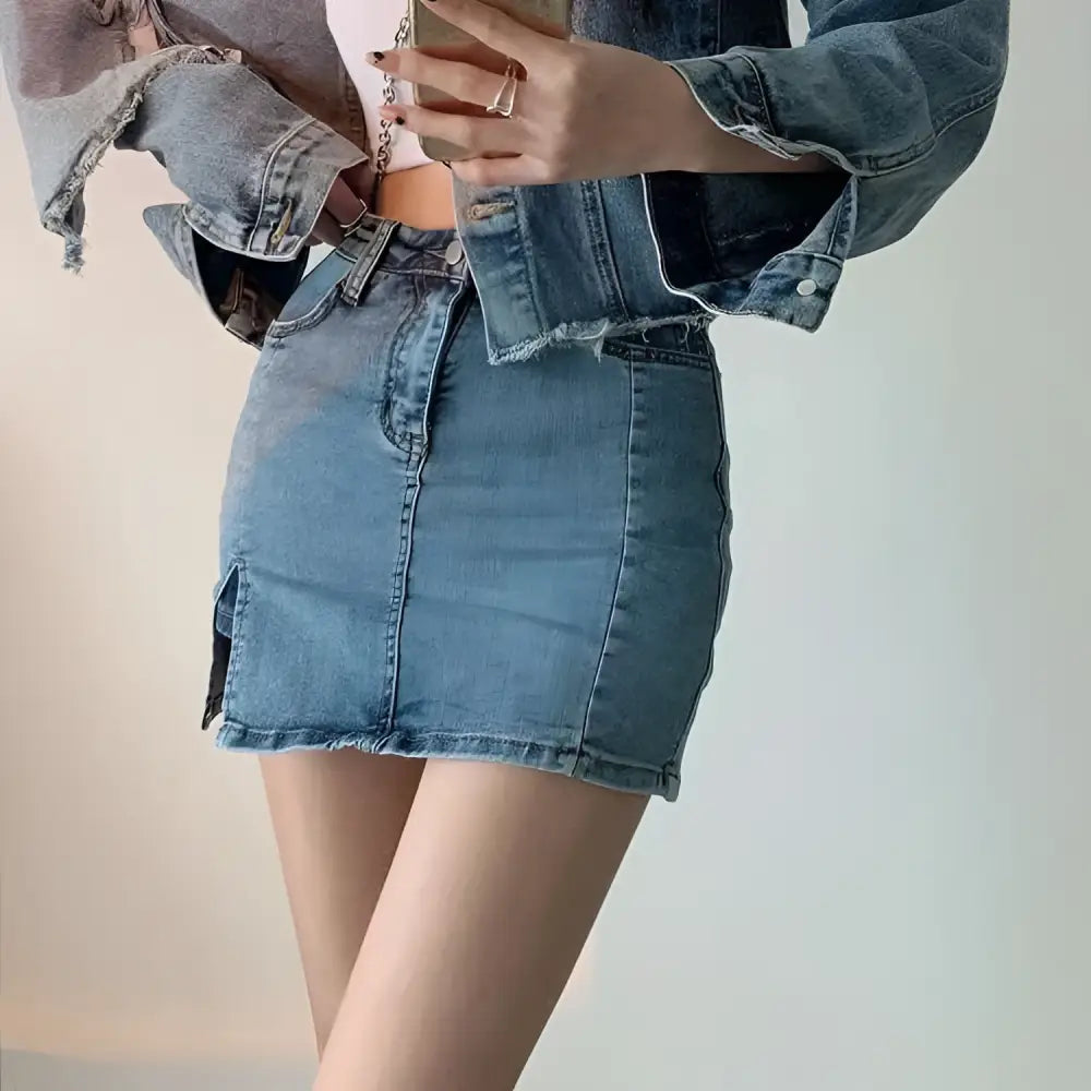Distressed black denim skirt with side slit featuring mid-rise fit, slightly faded blue wash, and frayed hem