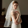 A delicate ivory lace bridal veil with double champagne edge metal hair comb and subtle gold trim along edges