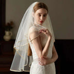 A delicate ivory lace bridal veil with double champagne edge metal hair comb and subtle gold trim along edges
