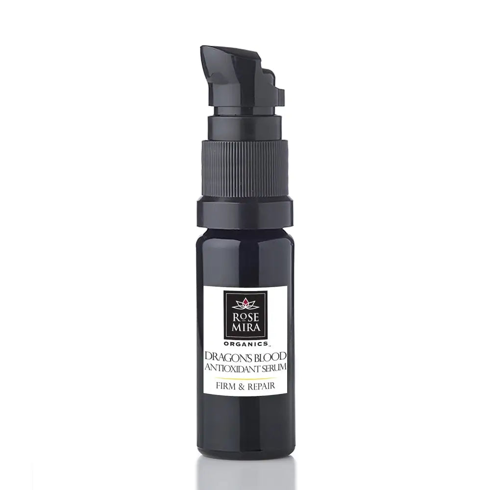 Black glass bottle with black pump dispenser labeled rose mira organics dragon’s blood antioxidant serum for firm and repair