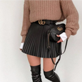 Black quilted gucci crossbody bag with gold-tone gg logo hardware complementing draped pleated knitted mini skirts