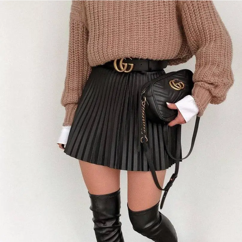 Black quilted gucci crossbody bag with gold-tone gg logo hardware complementing draped pleated knitted mini skirts