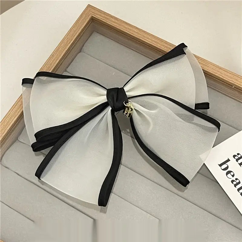 Elegant black and white handmade mesh bow hair clip with sheer fabric and a delicate gold charm for women