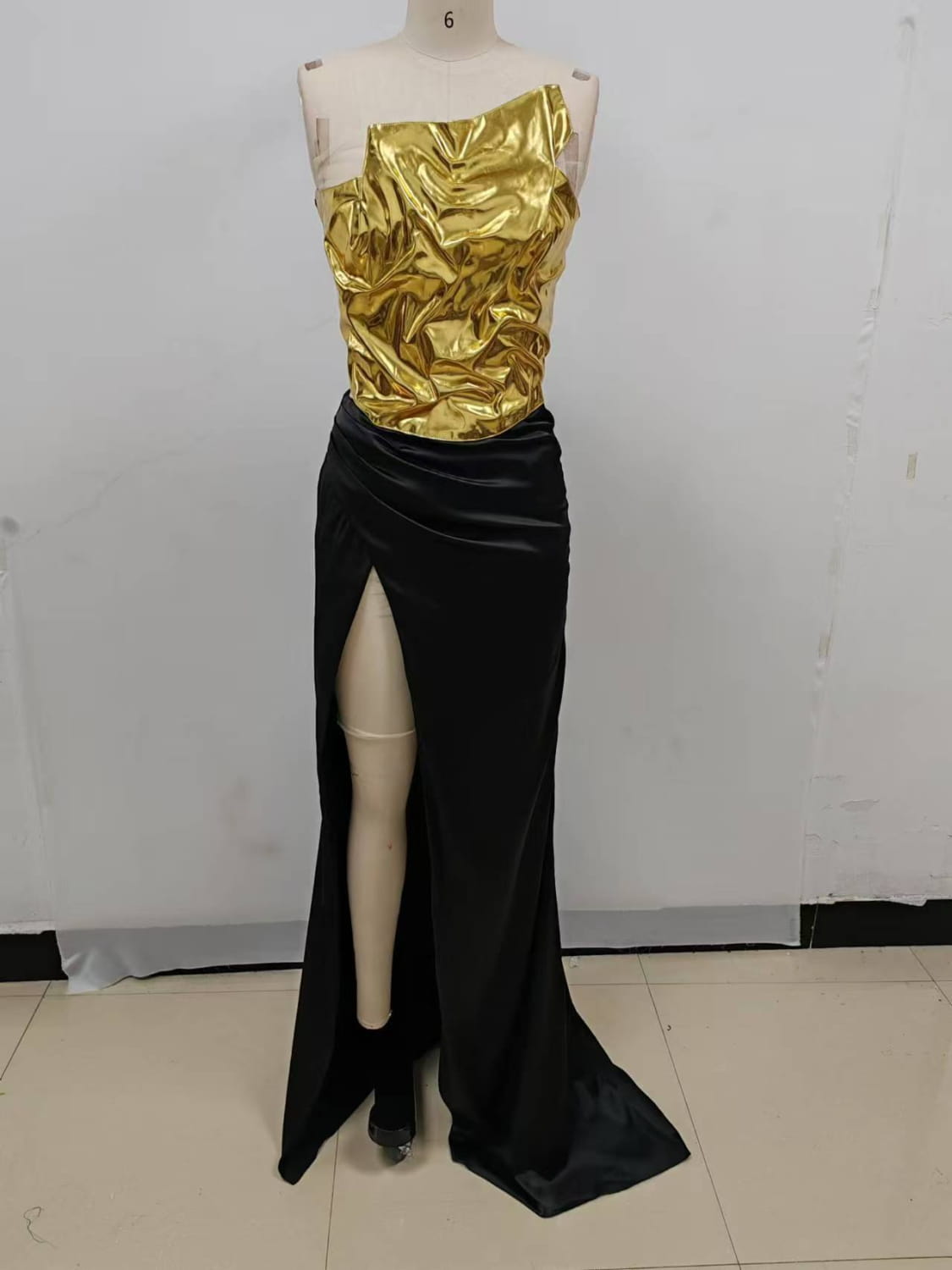 a one-shoulder slit mop black dress two-piece set featuring a shimmering gold metallic bodice with ruched texture paired with a sleek black velvet skirt with high slit and flowing train showcasing set sexy lacing elements