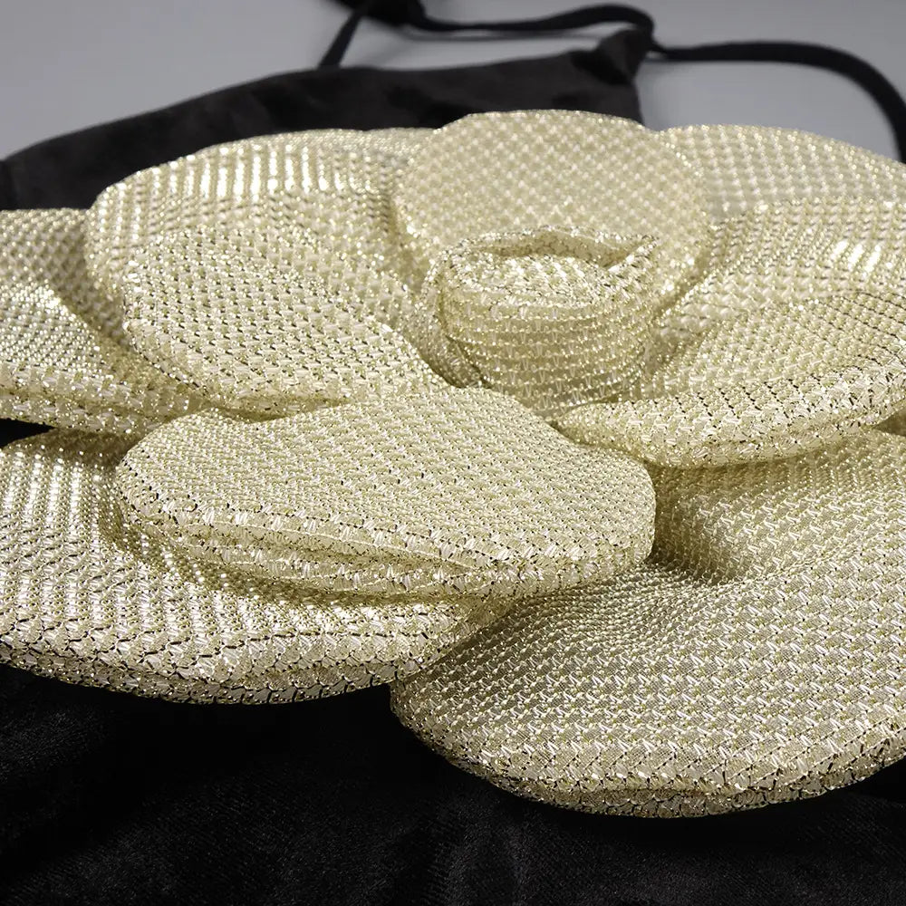 a shimmering gold beaded flower clutch bag with a textured mesh surface and layered petal design paired with a black camisole backless slim fit velvet floral gown