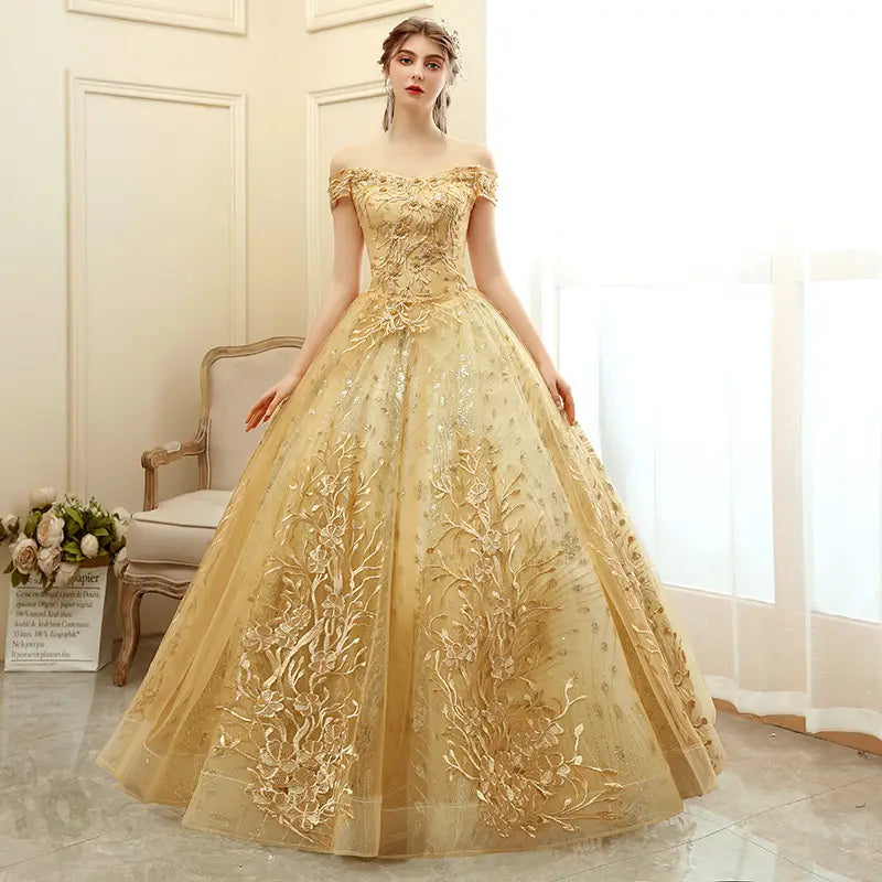 A shimmering gold off-the-shoulder solo performance costume featuring intricate floral embroidery and a voluminous tulle performance costume tutu skirt.