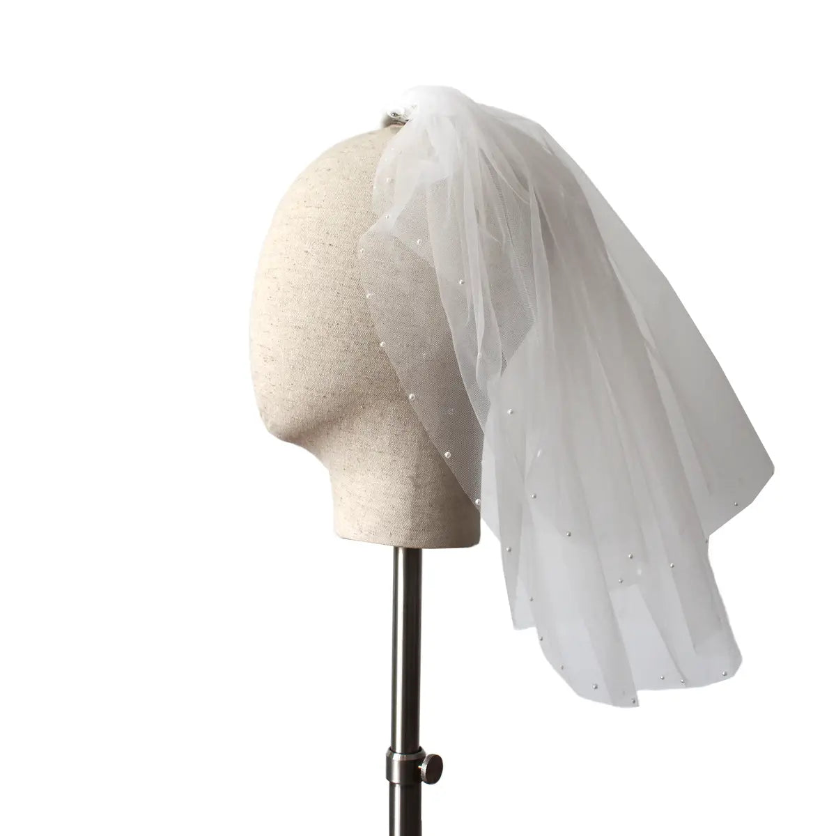A delicate white tulle retro short wedding lace floral veil with pearl embellishments along the edges displayed on a mannequin head for a short wedding bride headdress.