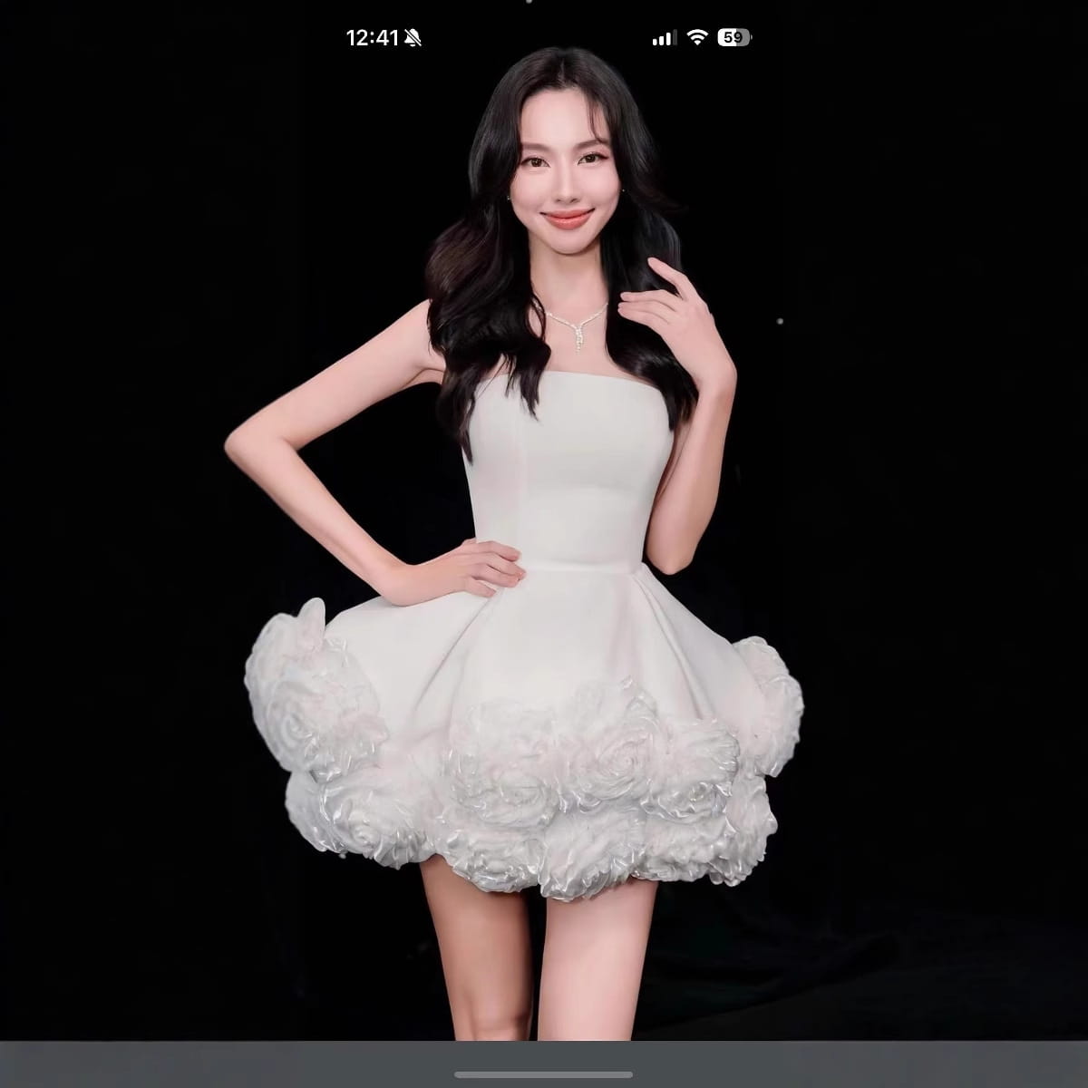 A white velvet strapless dress featuring a fitted bodice and a voluminous flower pettiskirt french with a short skirt made of lightweight fabric.