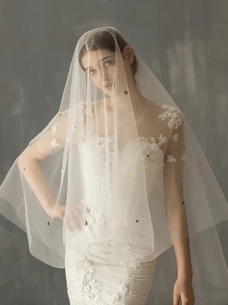 a delicate white lace bridal veil with subtle floral embroidery and star-shaped embellishments featuring mso-font-pitch variable mso-font-signature design elements