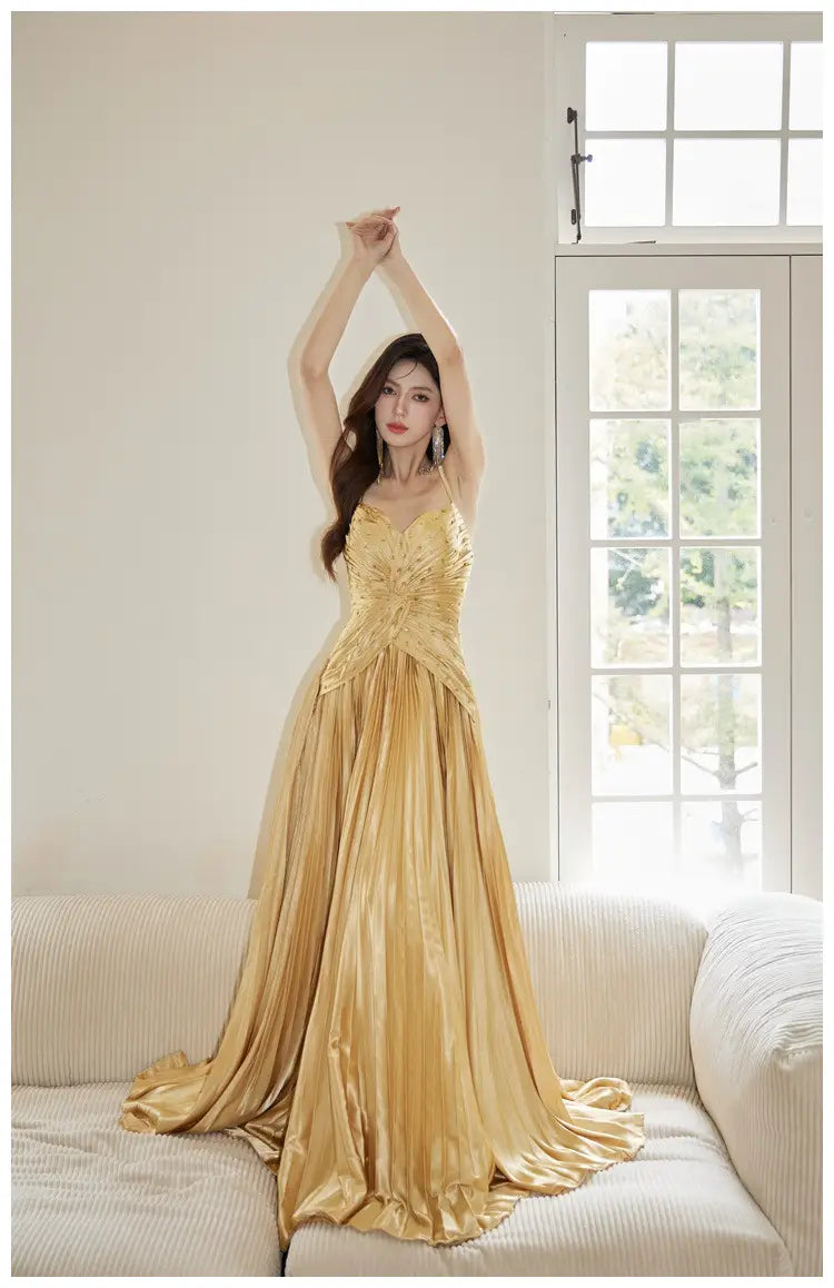 A shimmering gold satin heavy industry birthday dress featuring a fitted bodice and a flowing pleated skirt.