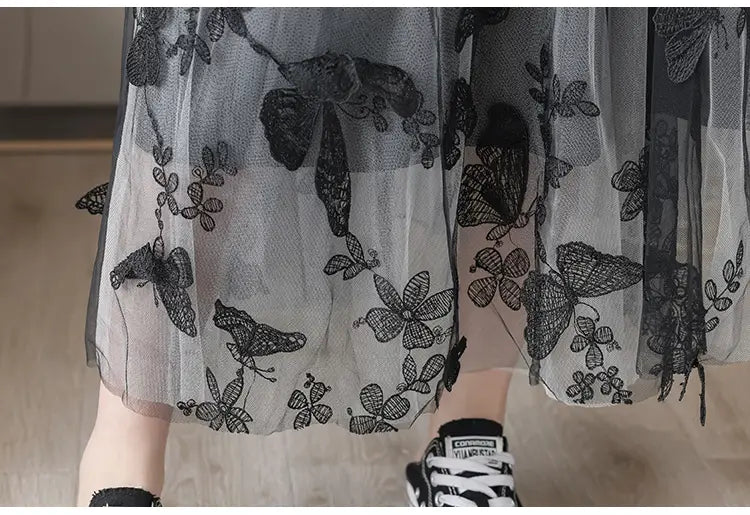 a sheer gray mid-length lace mesh skirt with intricate black butterfly and floral embroidery featuring embroidered bow lace details
