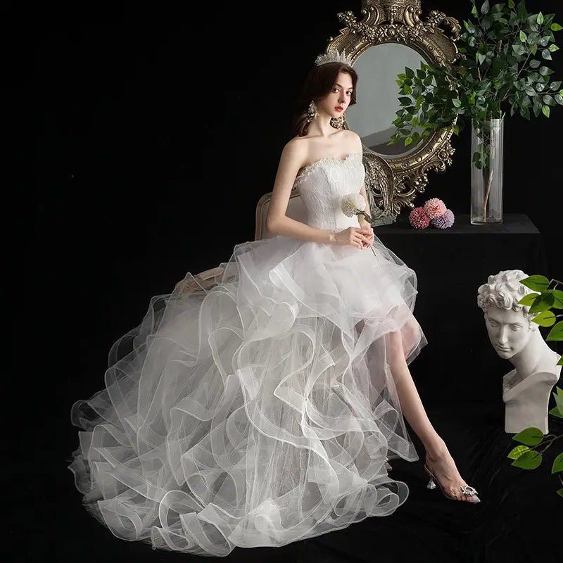 A flowing white small trailing wedding dress with a strapless bodice and layered tulle skirt.