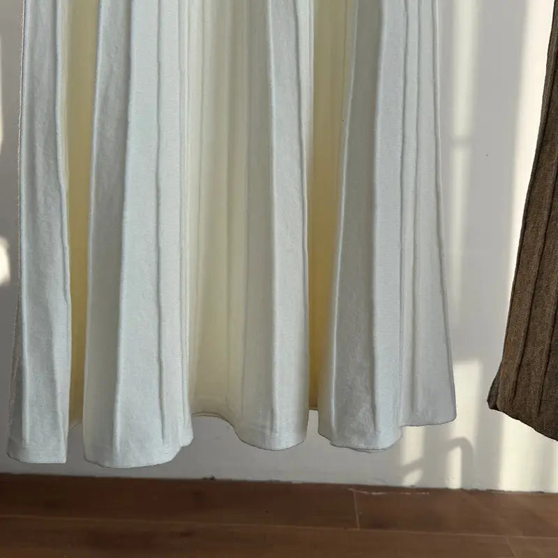 white pleated curtain with soft flowing folds and a subtle sheen complements the korean elastic waist knitted pleated midi skirt design.