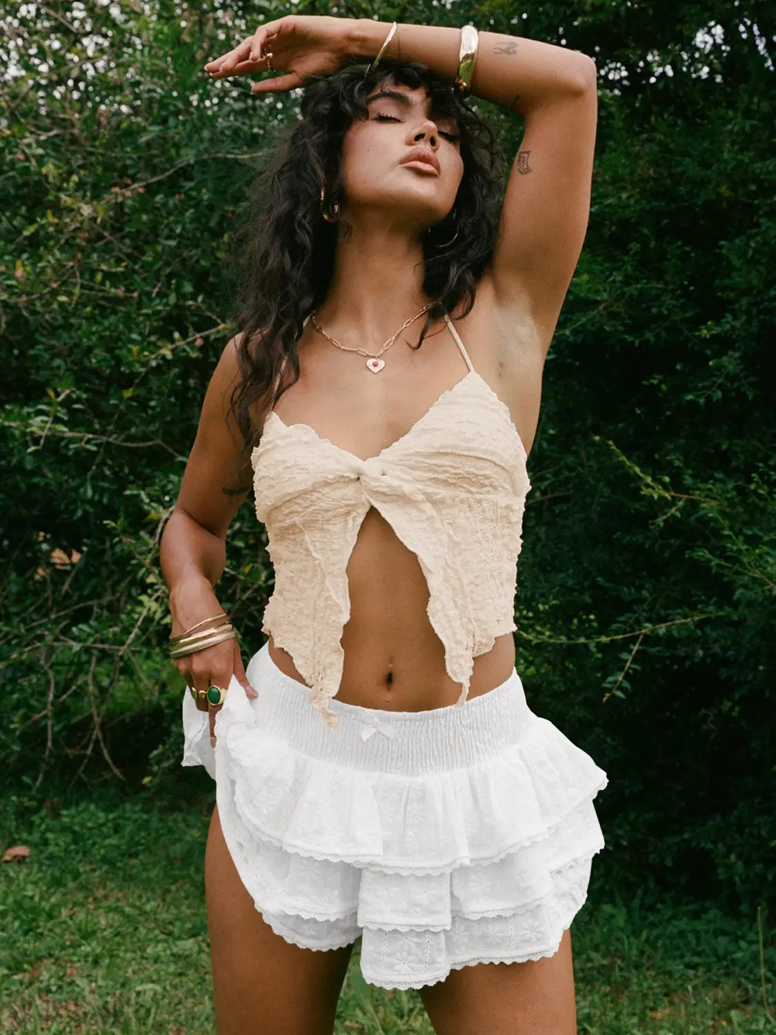 beige textured crochet crop top with front knot detail paired with white eyelet lace bow decorative bud skirt.