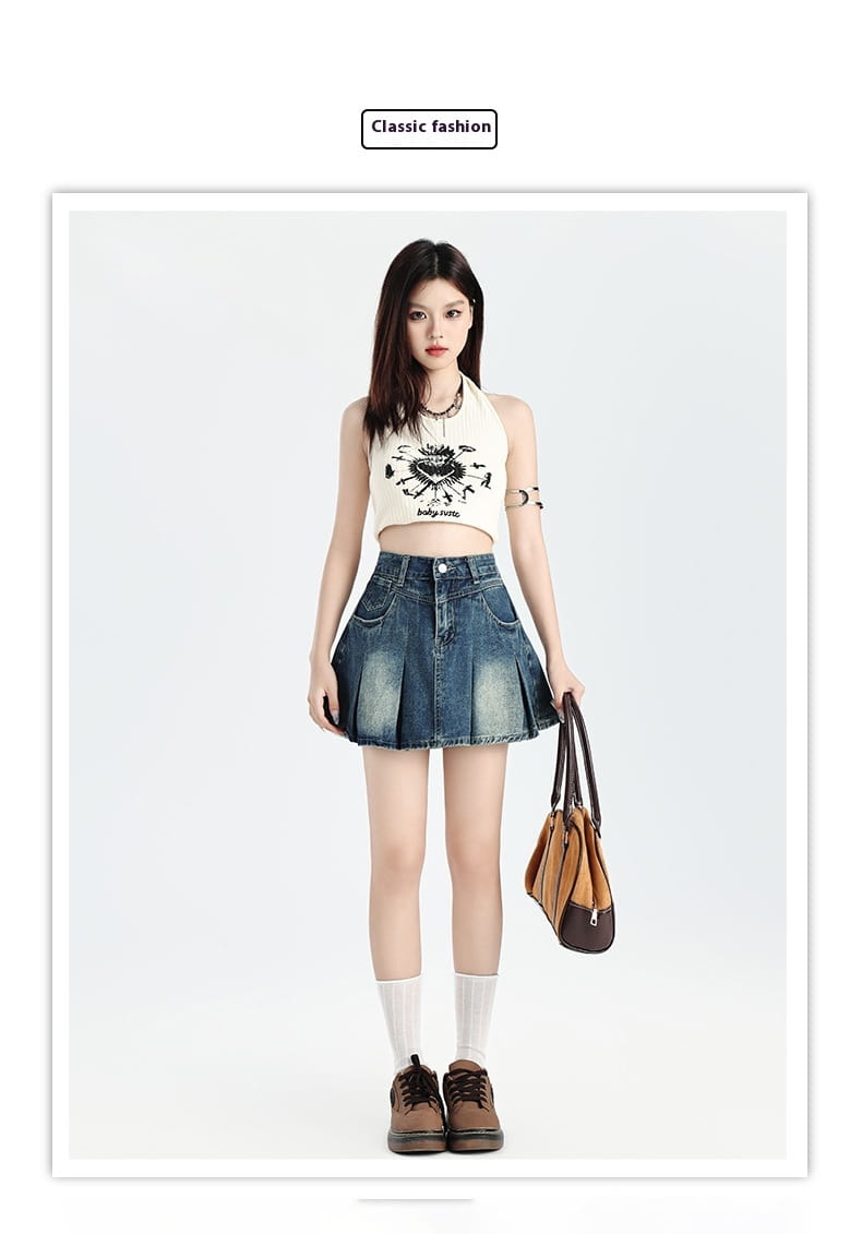 A woman wearing a cream-colored halter top with black graphic print paired with a vintage denim skirt high waist set, white socks, and brown shoes.