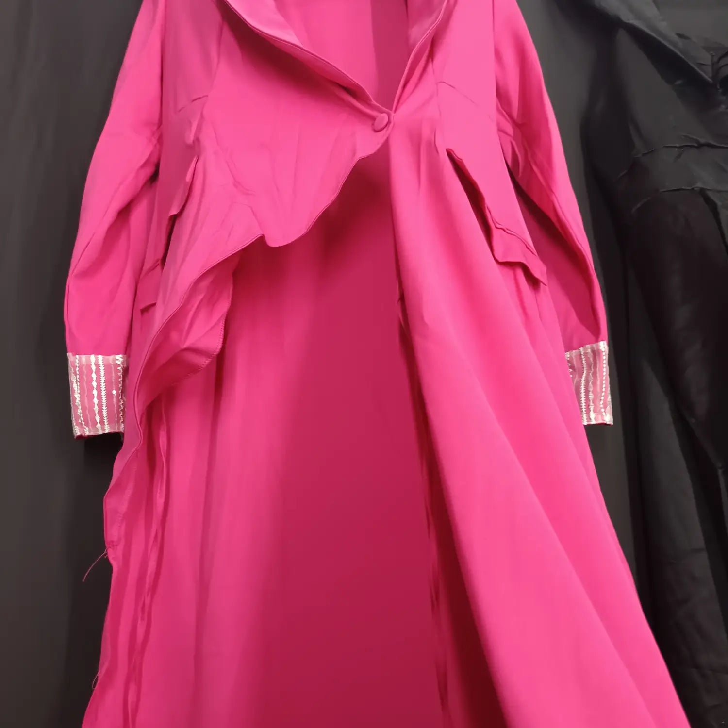 A vibrant fuchsia rose red suit coat with a flowing asymmetrical design and metallic striped cuffs highlighting the red suit collar embellishment.