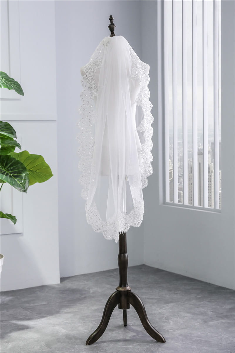 short veil soft mesh sequined lace white ivory featuring delicate white lace with intricate beaded detailing and scalloped edges displayed on a dark wooden mannequin stand