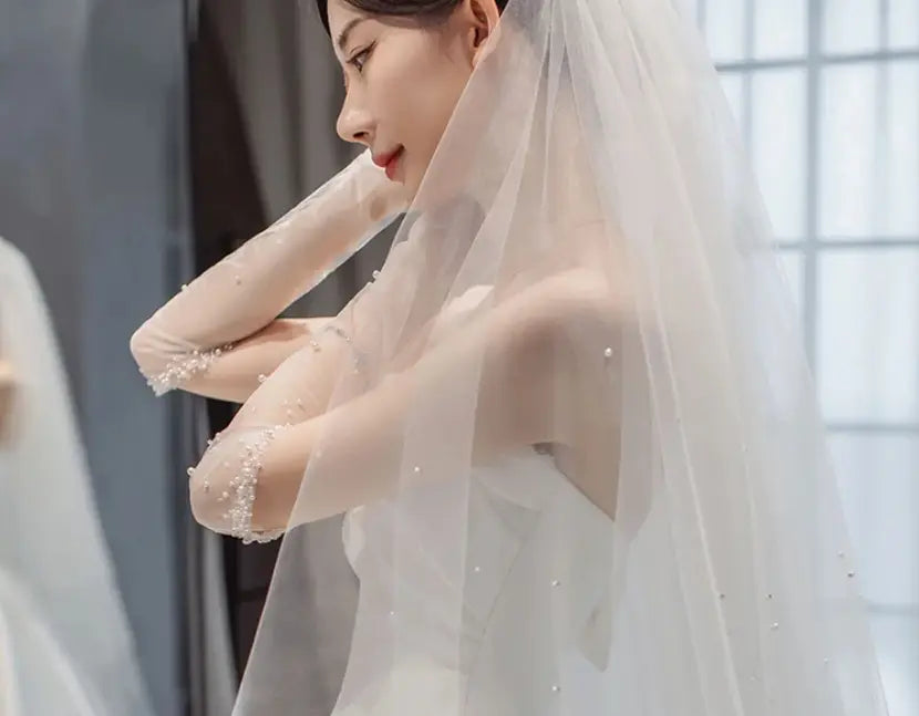 a delicate white tulle veil adorned with scattered pearl-like embellishments along the arm edges complements the temperament princess style french satin wedding gown