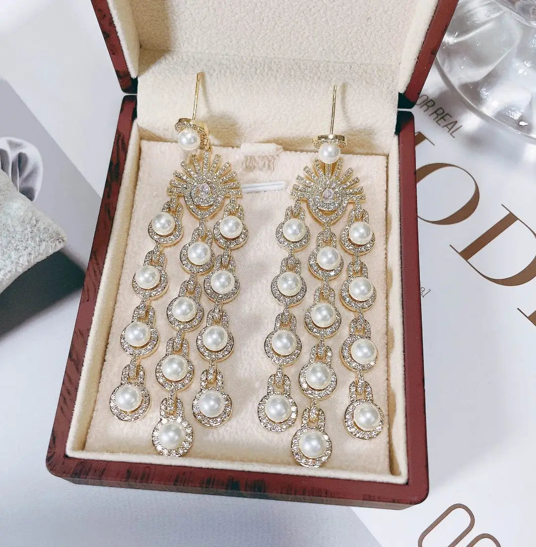 Gold-toned chandelier earrings featuring cascading rows of round white pearls and sparkling clear crystals in an ornate sunburst design with micro inlay zircon style beaded fringe.