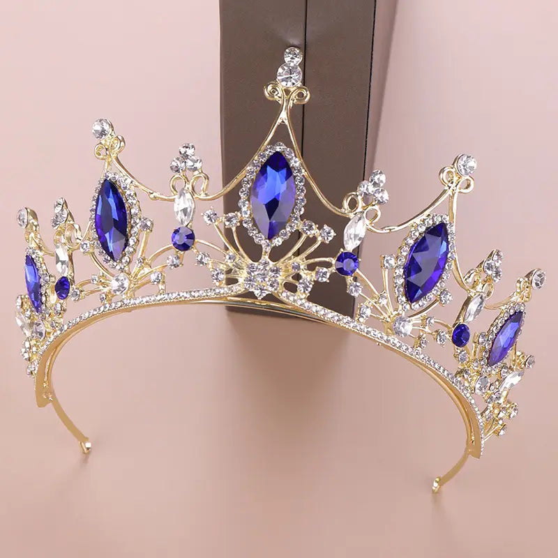 a crystal crown bride featuring a golden headband adorned with deep blue and clear crystal stones in an ornate regal design