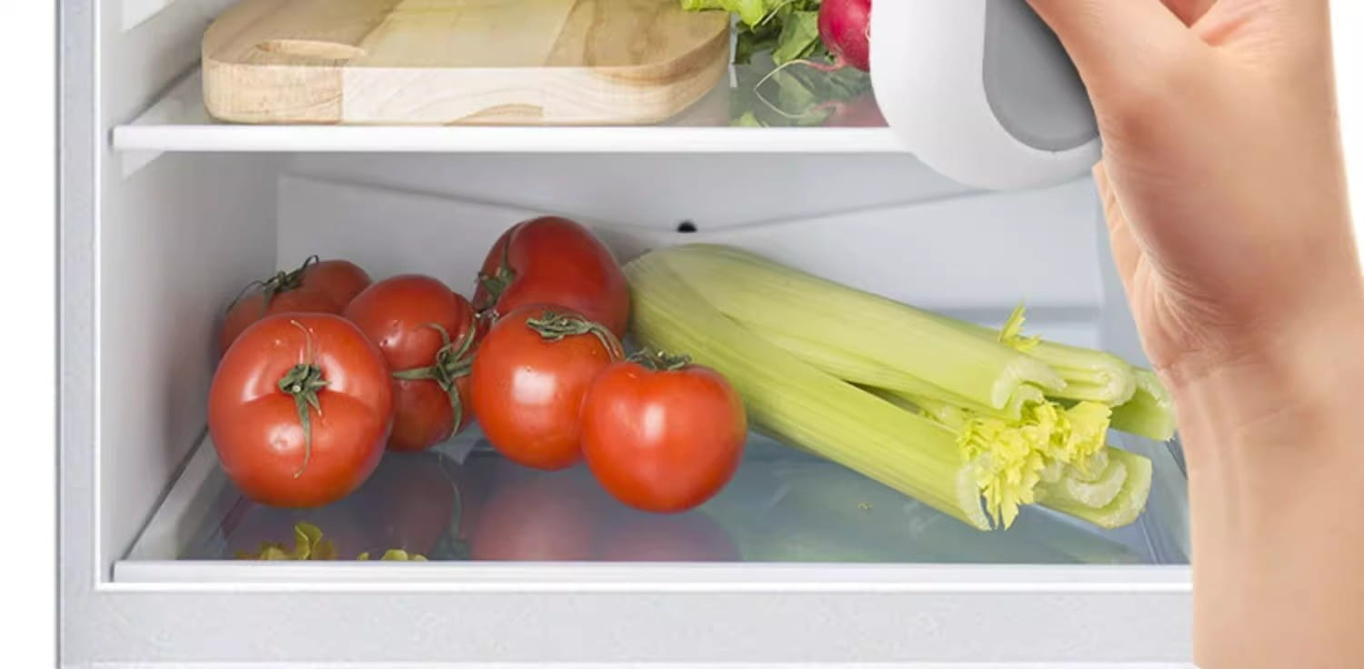 a hand reaches into a refrigerator to retrieve a white cylindrical container featuring a portable usb heat sealer and magnetic storage clip for convenient vacuum sealing.