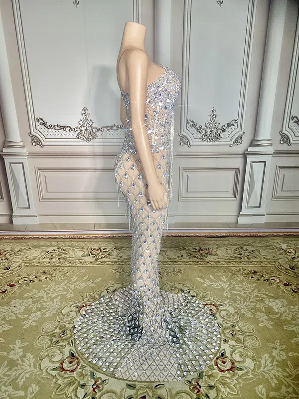 a shimmering silver beaded sexy elegant fishtail gown with a one-shoulder design and intricate diamond-like embellishments cascading down the back displayed on a mannequin from the back side