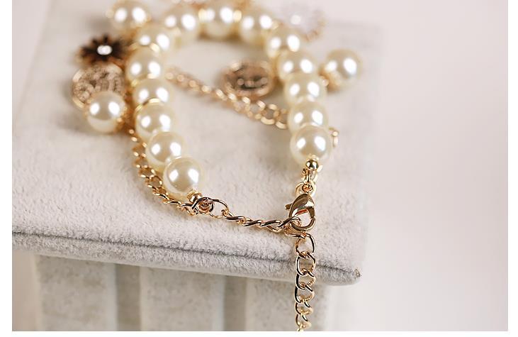 A delicate gold-toned necklace featuring cream pearls with ornate floral and circular charms designed to complement navy pearl flower bracelet and flower bracelet jewelry collections.