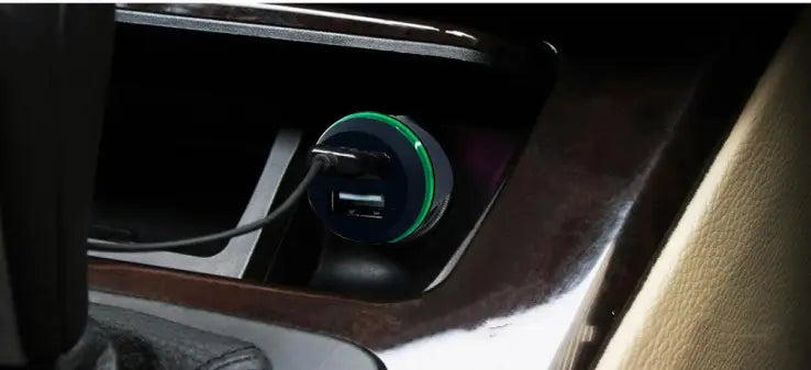 A sleek black dual usb car hands free phone music player with a vibrant green ring around its base and two usb ports connected by a black cable, designed for hands free phone use and long press control.