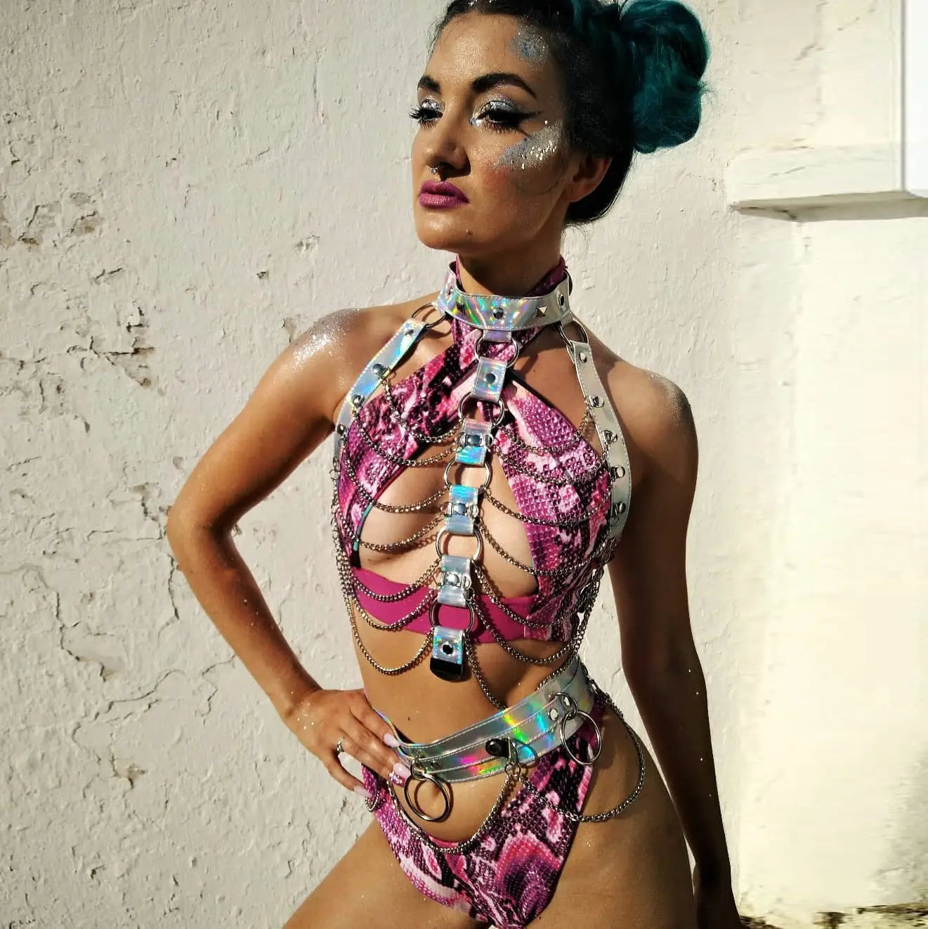 a creative versatile laser ladies belt bodysuit in shimmering pink and silver snakeskin pattern with metallic chains, buckles, and holographic accents
