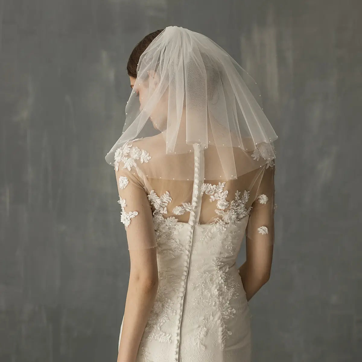 a delicate sheer white retro short wedding veil featuring floral lace detailing and a central back closure as a wedding bride headdress