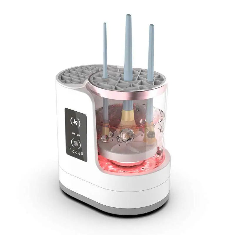 White and rose gold electric makeup brush cleaner with transparent cylindrical water tank and three blue brush handles submerged in bubbles