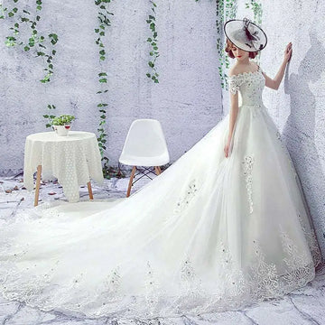 Elegant off-the-shoulder wedding dress in white with intricate lace detailing and a flowing train for bridal wear