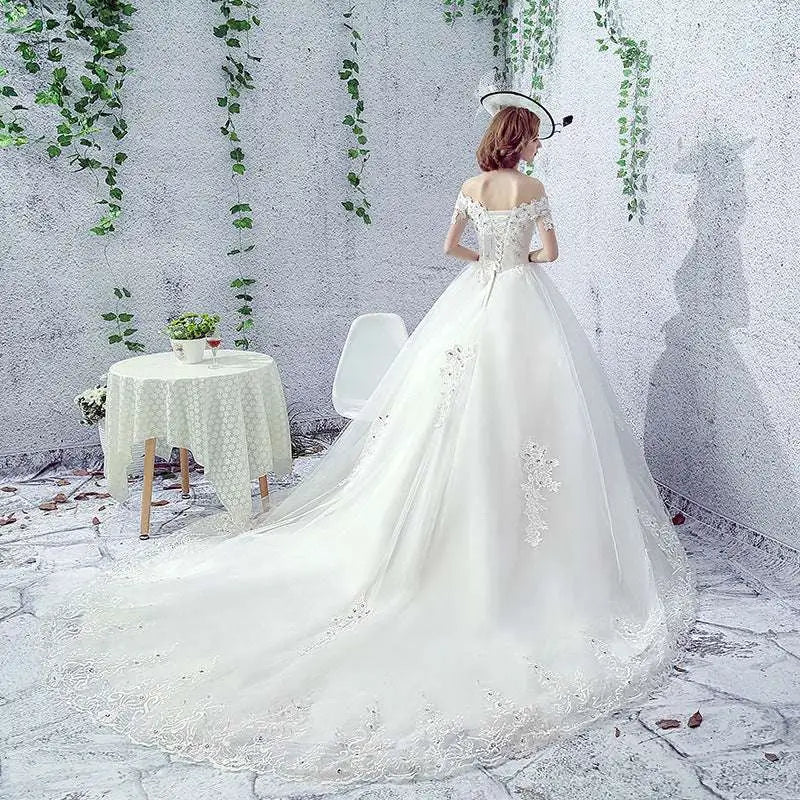 Elegant off-the-shoulder wedding dress in white with intricate lace detailing perfect for a bride with a trailing french veil