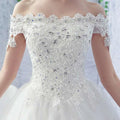 A white off-the-shoulder wedding dress featuring intricate lace and sparkling rhinestones perfect for brides