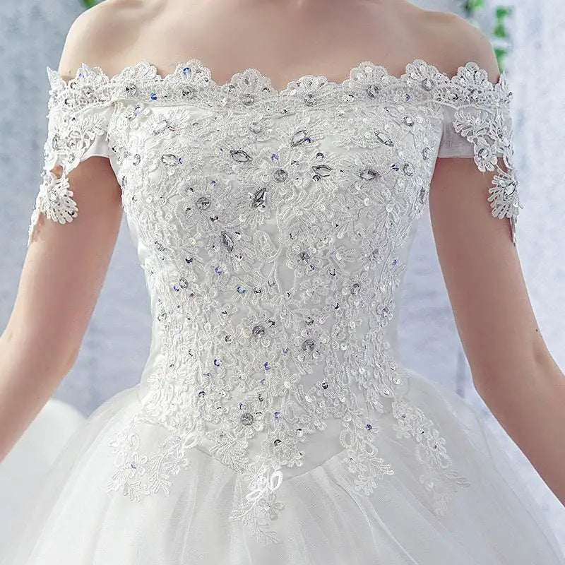 A white off-the-shoulder wedding dress featuring intricate lace and sparkling rhinestones perfect for brides