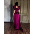 A woman wearing an elegant puff sleeve pleated slit magenta maxi dress in deep satin fabric with a back tie detail