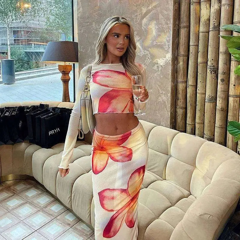 Elegant slim print skirt set featuring a vibrant pink and orange floral two-piece with long-sleeved crop top and high waist skirt