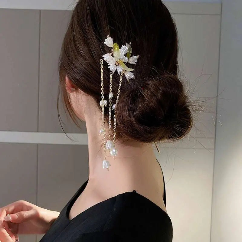 Elegant white floral temperament hairpin with delicate gold chains and dangling pearl-like beads for fashionable wear