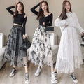 Three women model mid-length embroidered bow lace mesh skirts in sheer gray and white with black butterfly embroidery