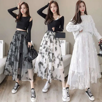 Three women model mid-length embroidered bow lace mesh skirts in sheer gray and white with black butterfly embroidery