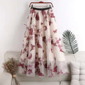 A flowing sheer white lace mesh skirt mid-length with embroidered bow lace and red butterfly embroidery hangs on a wooden hanger