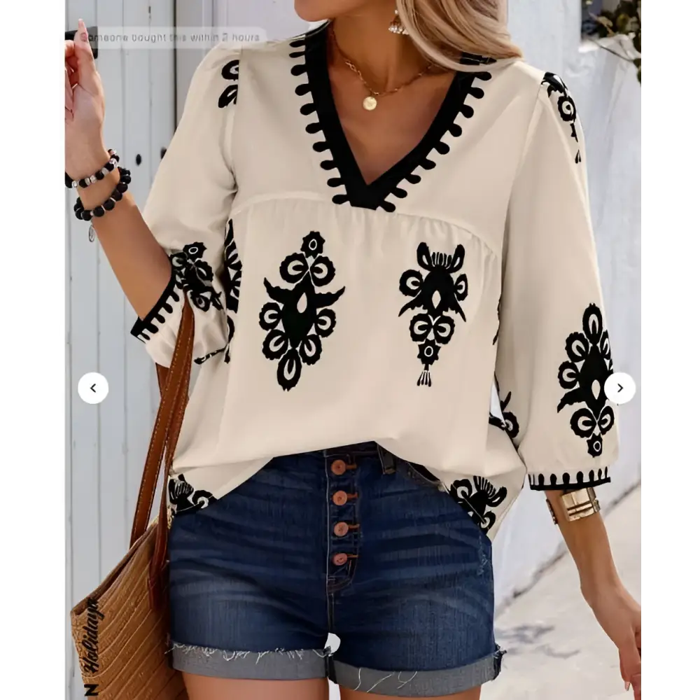 Cream-colored casual vacation blouse with black embroidered floral patterns and a v-neckline for embroidered casual vacation wear