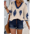 Cream-colored casual vacation blouse with navy blue embroidered floral patterns and a v-neckline for embroidered casual vacation wear