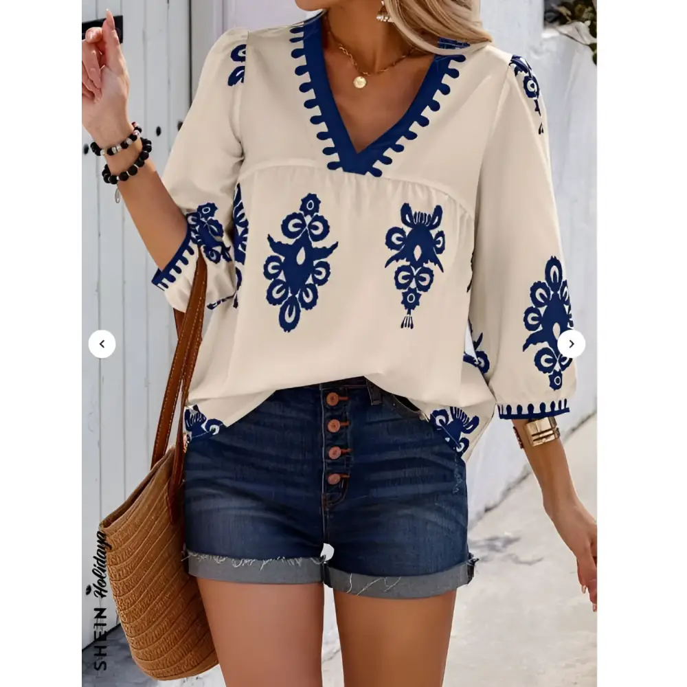 Cream-colored casual vacation blouse with navy blue embroidered floral patterns and a v-neckline for embroidered casual vacation wear